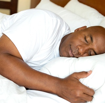 A middle-aged man wearing a white t-shirt and sleeping with the help of relaxation techniques