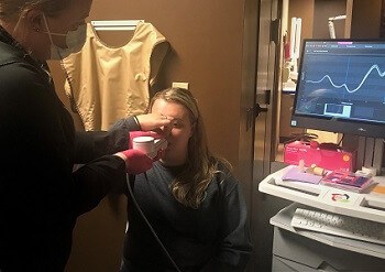 A staff member using the Eccovision Rhinopharyngometry on a female patient during an appointment