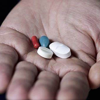 Hand holding four different pills