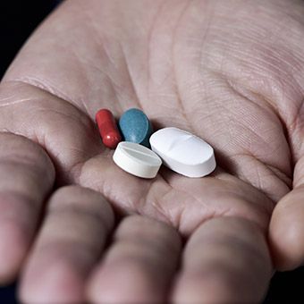 Hand holding four different pills