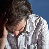 Man with head down and him holding it