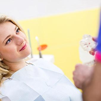 Woman in dental chair smiling at dentist