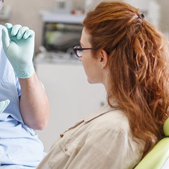 Woman in dental chair looking at dentist