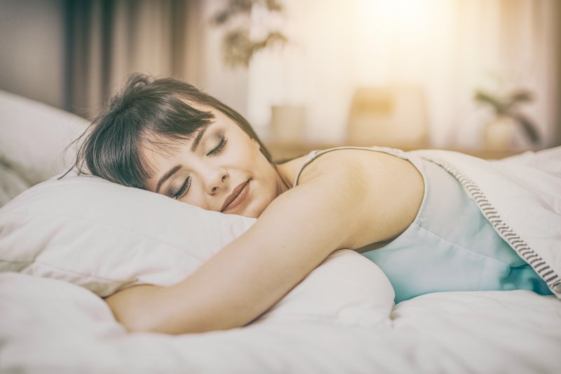 a young woman lying on her stomach and asleep on her pillow