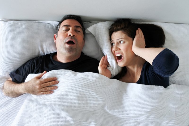 woman covers ears because of husband’s sleep apnea in Powell