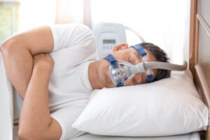 Man sleeping wearing CPAP machine. 